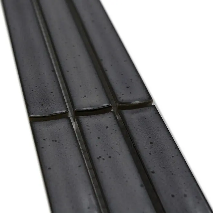 Fliesenbordüre YBO CS26 - 6,9 x 29,6 cm, Grau, Glänzend - Nahaufnahme von schlanken, dunkelgrauen Keramikfliesen mit einer leicht glänzenden Oberfläche und unregelmäßigen Farbsprenkeln. Ideal für moderne Akzente.