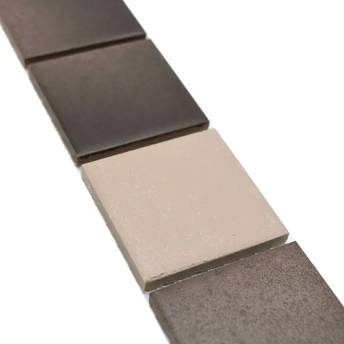 Fliesenbordüre YBO CD218 - 4,8 x 30,6 cm, Mix Grau, Matt - Nahaufnahme von quadratischen, braunen und beigen Keramikfliesen, die ein minimalistisches und modernes Design zeigen.