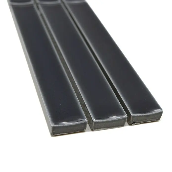 Fliesenbordüre YBO CS36 - 6,9 x 29,6 cm, Schwarz, Glänzend - Drei schmale, anthrazitfarbene Glasfliesen liegen nebeneinander und zeigen ihre glänzende Oberfläche. Perfekt für stilvolle Akzente im Bad oder Küche.