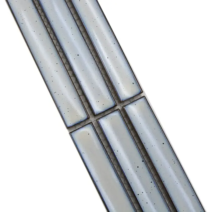 Fliesenbordüre YBO CS66 - 6,9 x 29,6 cm, Weß, Glänzend - Nahaufnahme von länglichen, hellgrauen Keramikfliesen mit dunklen Akzenten, die ein modernes und stilvolles Design zeigen.