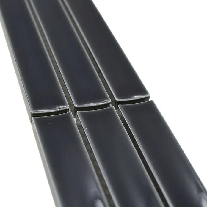 Fliesenbordüre YBO CS36 - 6,9 x 29,6 cm, Schwarz, Glänzend - Nahaufnahme von schmalen, grauen glänzenden Keramikfliesen, die linear angeordnet sind und ein modernes Designelement darstellen.