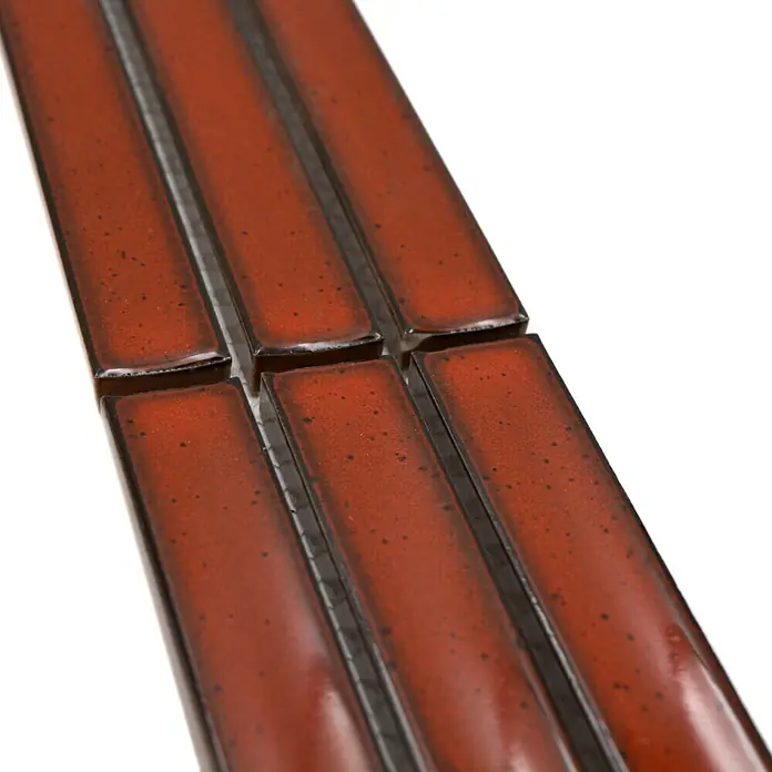 Fliesenbordüre YBO CS56 - 6,9 x 29,6 cm, Rot, Glänzend - Nahaufnahme von länglichen, rot glasierten Keramikfliesen mit dunklen Akzenten, die in einer Reihe angeordnet sind und ein modernes Designelement darstellen.