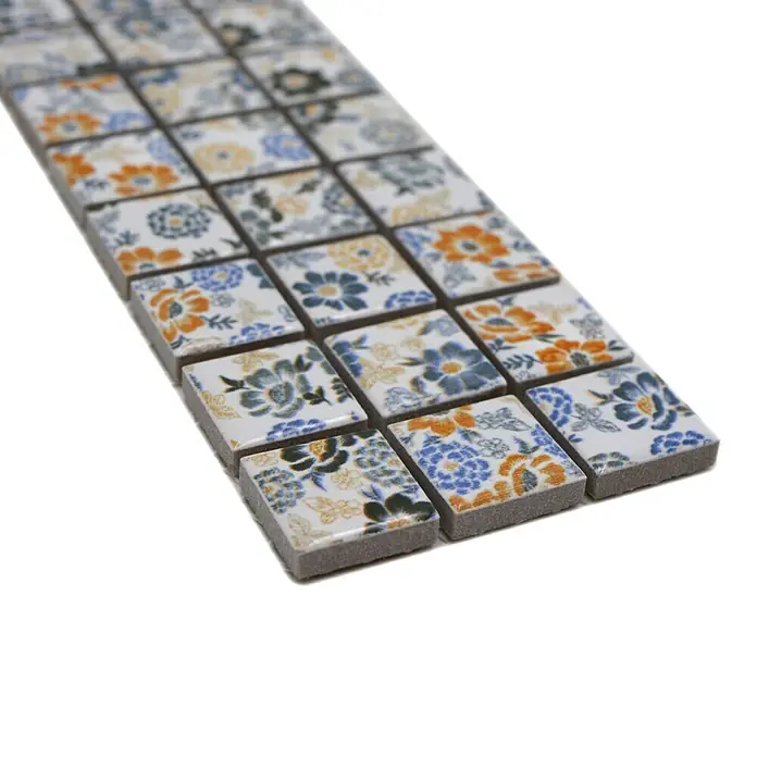 Fliesenbordüre Spring YBO FLOWER - 6,1 x 30,5 cm, Mix Weiß, Glänzend - Nahaufnahme von floralen Mosaikfliesen in Weiß, Blau und Orange, die ein elegantes und dekoratives Element für jeden Raum darstellen.