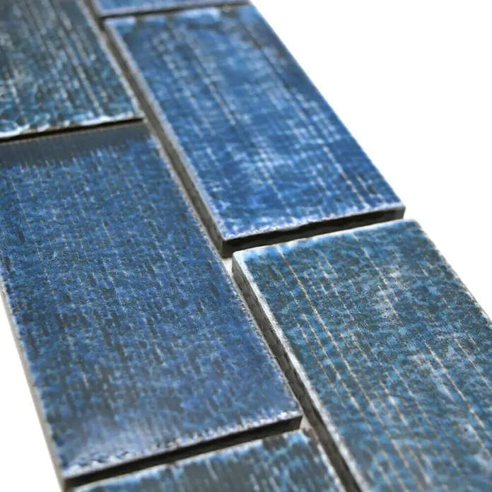 Fliesenbordüre YBO KAS8 - 4,7 x 29,7 cm, Grün/Blau, Glänzend - Nahaufnahme von blauen rechteckigen Fliesen mit dunklen Fugen, die ein strukturiertes Muster zeigen.