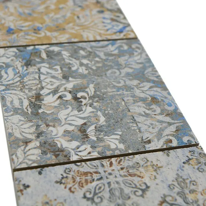 Fliesenbordüre Vestige YBO CV95MSC - 29 x 9,5 cm, Bunt, Matt - Nahaufnahme von dekorativen Keramikfliesen mit einem komplexen floralen Muster und einer Palette von sanften Blau-, Braun- und Grautönen.
