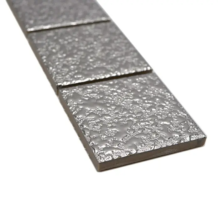 Fliesenbordüre Gehämmert YBO SB595 - 4,8 x 30,6 cm, Silber, Glänzend - Nahaufnahme einer Reihe von strukturierten Metallfliesen mit einem einzigartigen, reflektierenden Finish, ideal für moderne Designprojekte.