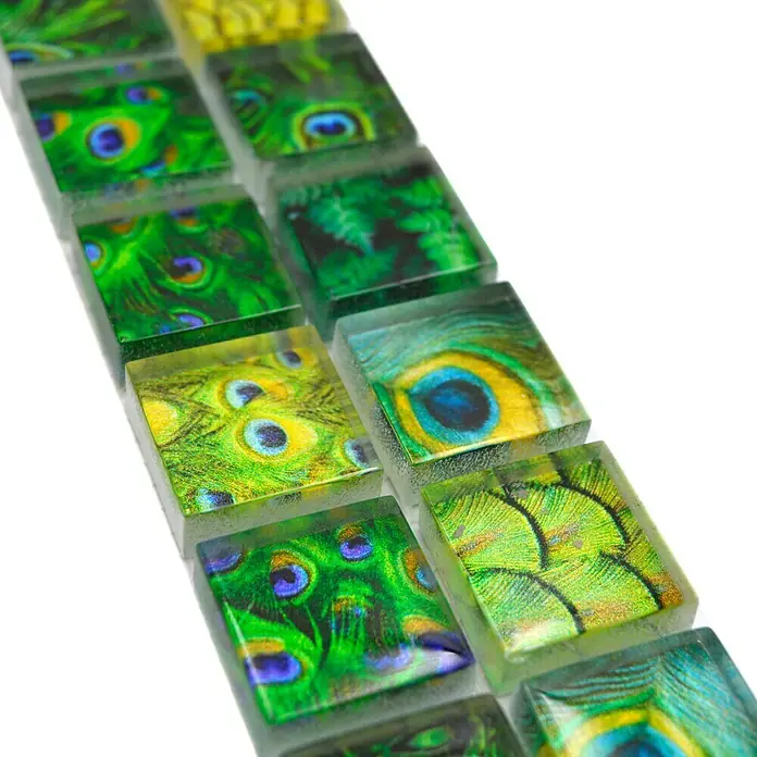Fliesenbordüre Wildlife YBO WL84 - 29,8 x 4,8 cm, Grün, Glänzend - Nahaufnahme von Mosaikfliesen mit Pfauenfeder-Design, die sich ideal für die Dekoration eignen und einen Hauch von Eleganz verleihen.
