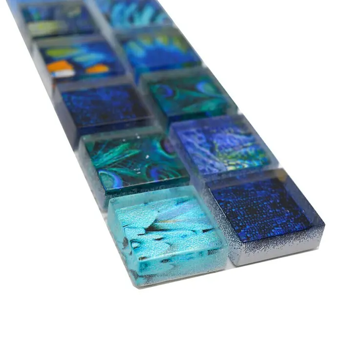 Fliesenbordüre Wildlife YBO WL74 - 29,8 x 4,8 cm, Blau, Glänzend - Nahaufnahme eines Musters aus blauen und türkisfarbenen Glasmosaikfliesen auf einer weißen Oberfläche.
