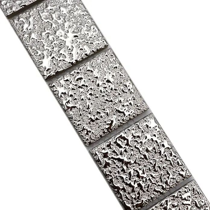 Fliesenbordüre Gehämmert YBO SB595 - 4,8 x 30,6 cm, Silber, Glänzend - Nahaufnahme eines silberfarbenen Mosaikfliesenbandes mit einem strukturierten, tropfenförmigen Design, das ein modernes, reflektierendes Element für die Inneneinrichtung bietet.
