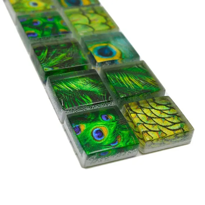 Fliesenbordüre Wildlife YBO WL84 - 29,8 x 4,8 cm, Grün, Glänzend - Nahaufnahme einer Reihe von dekorativen Glasmosaikfliesen mit Pfauenfedermotiven in Grün-, Blau- und Gelbtönen.