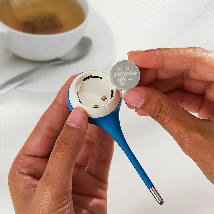 Energizer Knopfzelle - CR2032, 3 V, 6 Stk. - Nahaufnahme eines Fieberthermometers, das eine CR2032 Energizer 3-Volt-Batterie benötigt, mit einer Tasse Tee im Hintergrund.