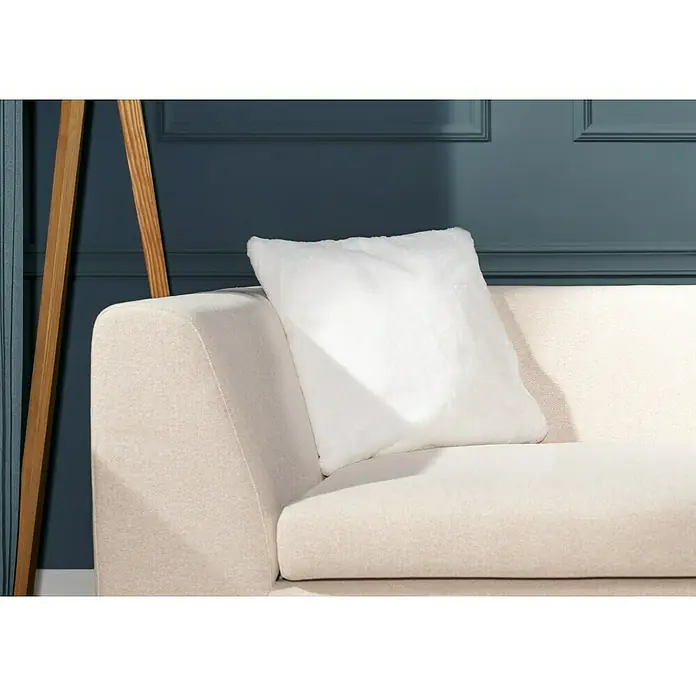 Kissen Happy - Elfenbein, 48 x 48 cm, 100 % Polyester - Nahaufnahme eines beigen Sofas mit einem flauschigen, quadratischen weißen Kissen, das Komfort und Stil für die Wohnkultur bietet.