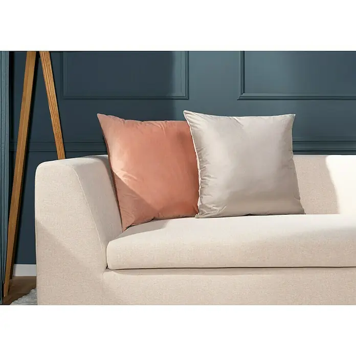 Kissen Finja - Driftwood, 60 x 60 cm, 100 % Polyester - Nahaufnahme eines beigen Sofas mit einem pfirsichfarbenen und einem hellgrauen Kissen, das eine gemütliche und stilvolle Wohnatmosphäre suggeriert.