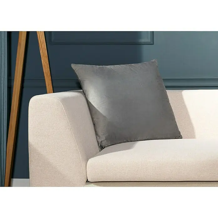 Kissen Finja - Micro Chip, 60 x 60 cm, 100 % Polyester - Nahaufnahme eines quadratischen, grauen Kissens, das auf einer cremefarbenen Couch mit Holzbeinen vor einer blaugrünen Wand steht.