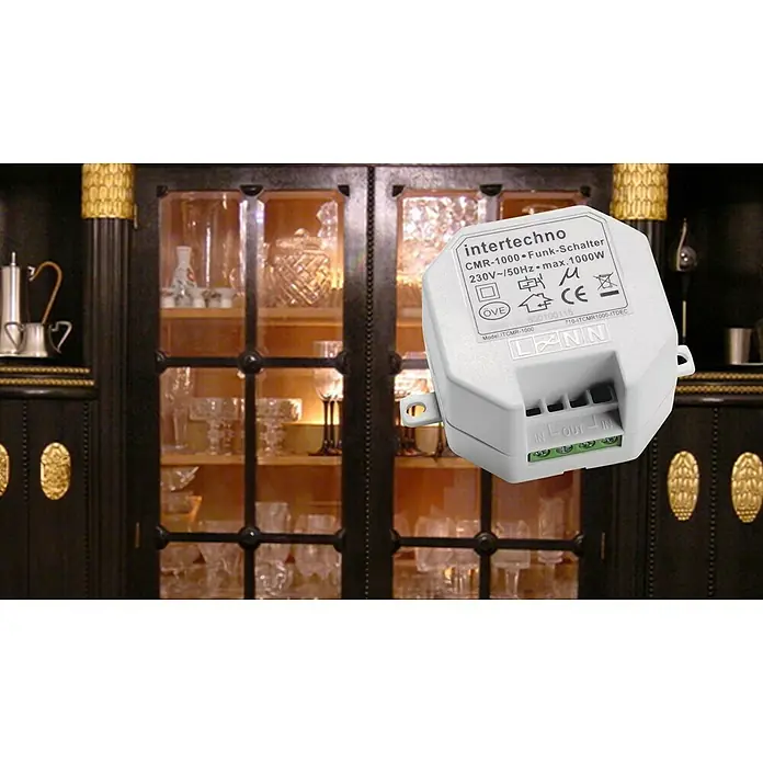 Intertechno Funk-Einbauschalter CMR-1000 - 1.000 W, Reichweite ca.: 30 m - Nahaufnahme eines Intertechno CMR-1000 Funk-Schalters vor einem dunklen Vitrinenschrank.