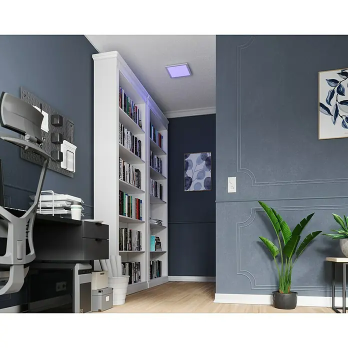 Tween Light LED-Panel RGB-RC-CCT-DIM - 15,5 W, L x B x H: 30 x 30 x 5,5 cm, Weiß, RGBW - Bücherregal in einem Arbeitszimmer mit einem modernen Schreibtisch und einem Stuhl. Die blauen Wände verleihen dem Raum eine ruhige Atmosphäre.