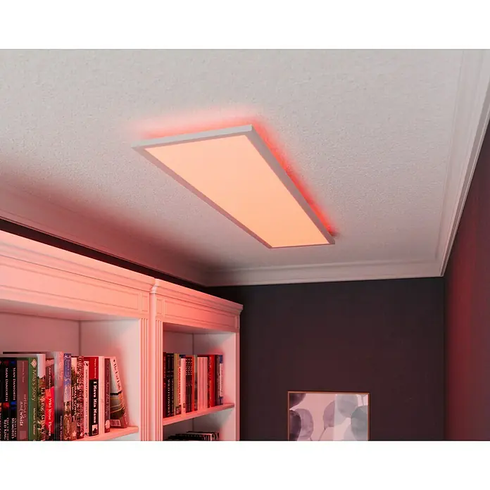 Tween Light LED-Panel RGB-RC-CCT-DIM - 32,5 W, L x B x H: 120 x 30 x 5,5 cm, Weiß, RGBW - Eine LED-Deckenleuchte in einem Raum mit Bücherregal, die ein warmes, rotes Licht ausstrahlt, sorgt für eine gemütliche Atmosphäre.
