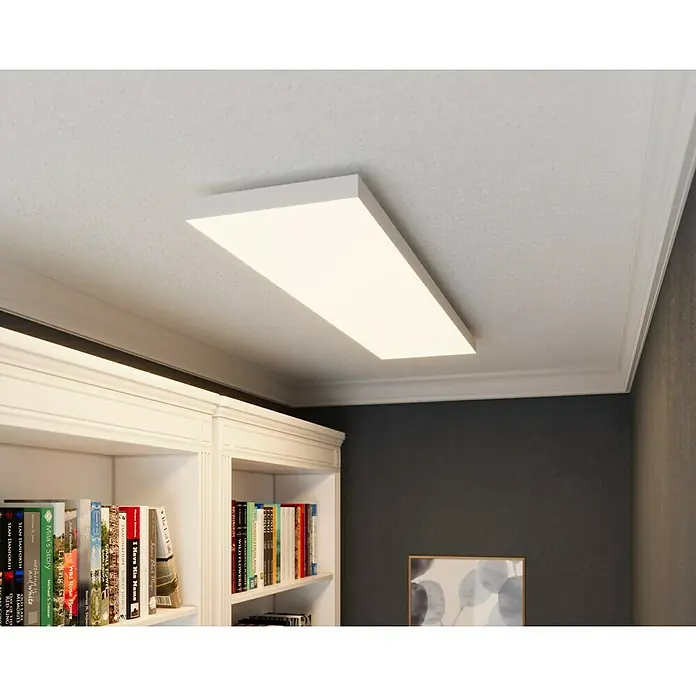 Tween Light LED-Panel Frameless - 34 W, L x B x H: 120 x 30 x 4,4 cm, Weiß, Mehrfarbig - Eine rechteckige LED-Deckenleuchte in einem Raum mit Bücherregal und dunklen Wänden. Das Licht ist hell und erhellt den Raum.