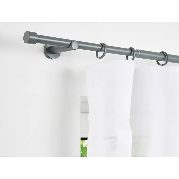 Stilgarnitur Cosy - Dark Grey, Auszugslänge: 160 cm - 280 cm - Nahaufnahme einer grauen Gardinenstange mit weißen Vorhängen, die an der Wand befestigt sind. Minimalistisches und stilvolles Design.