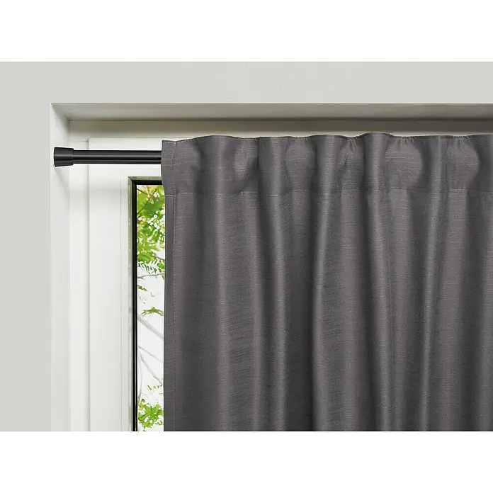 Spannstange Stretch - Schwarz, Auszugslänge: 80 cm - 130 cm - Nahaufnahme einer grauen Gardine, die an einer schwarzen Gardinenstange vor einem Fenster hängt und einen stilvollen Sichtschutz bietet.