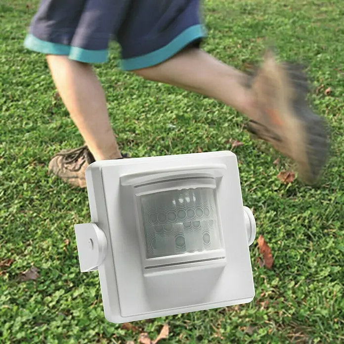 Intertechno Funk-Bewegungsmelder Outdoor PIR-6000 - Weiß, Erfassungswinkel: 110 ° - Bewegungsmelder in Weiß im Fokus, während eine Person im Hintergrund vorbeiläuft. Ideal für die Sicherheit rund ums Haus.