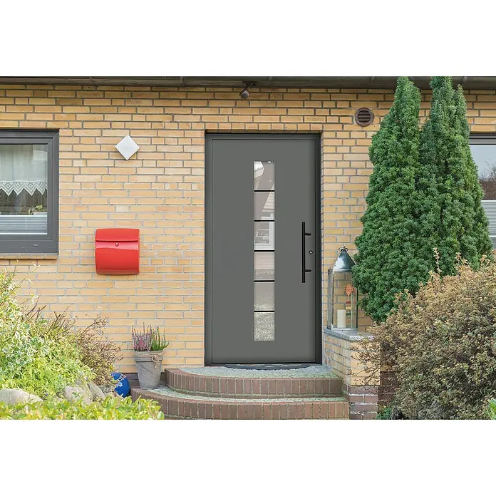 Splendoor Haustür Premium Bonn - 100 cm x 210 mm, DIN Anschlag: Rechts, Graualuminium - Graue Haustür mit Glaseinsätzen und schwarzem Griff an gelber Backsteinfassade mit rotem Briefkasten und Grünpflanzen im Vorgarten.
