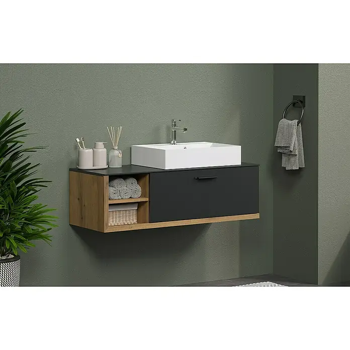 Trendteam Synnax Badmöbel-Set - 120 cm, Coast Evoke Eiche/Anthrazit, Matt, Maße Waschbecken: B: 60 cm - Modernes Badezimmer-Waschbecken mit Holzregal und Schublade in Anthrazit. Handtuchhalter und grüne Wand im Hintergrund sorgen für ein stilvolles Ambiente.