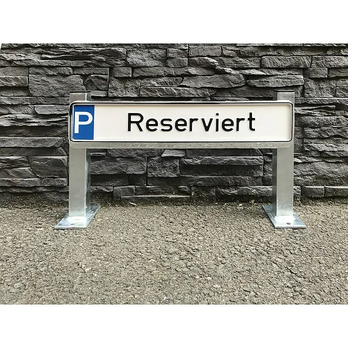 Schake Halterung - 520 x 350 mm, Stahl, Aufdübeln - Reservierter Parkplatz mit blauem P-Schild und schwarzer Schrift auf weißem Grund, vor einer grauen Steinwand.