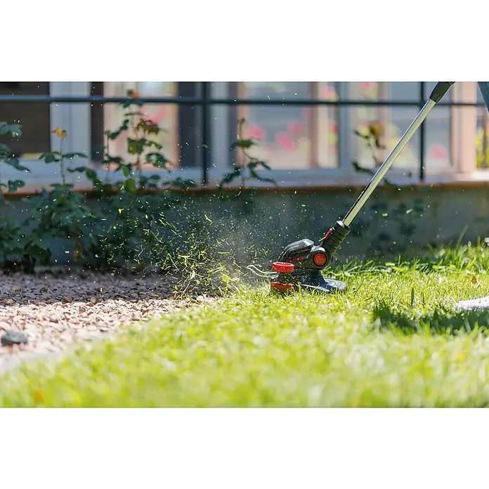 Ducati Recortabordes de batería DGT401L - 40 V, 2,5 Ah, Iones de litio, Sin batería, Ancho de corte hilo: 30 cm - Un cortabordes en acción, cortando hierba y enviando pequeños trozos de hierba al aire, creando un borde limpio en el césped.