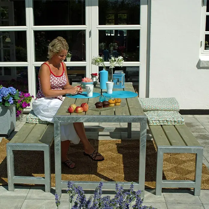 Plus Sitzgruppen-Set - 3 -tlg., Ohne Rückenlehne - Helle Gartenszene mit einem robusten Holztisch und passenden Bänken auf einem Außenteppich, ideal für entspannte Stunden im Freien.