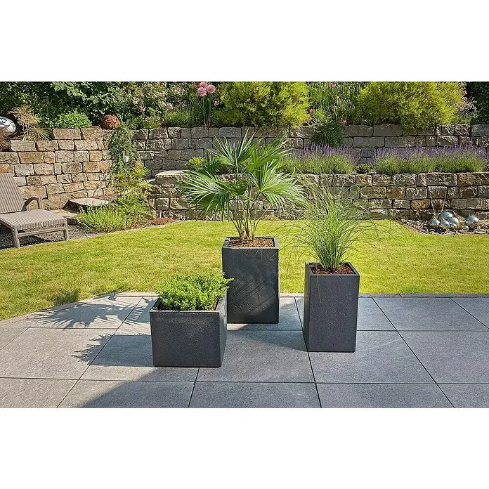Scheurich Pflanzsäule eckig C-Cube - Außenmaß (L x B x H): 38 x 38 x 53,7 cm, Kunststoff, Schwarz - Drei graue Pflanzkübel mit verschiedenen Pflanzen stehen auf einer Terrasse, umgeben von einem gepflegten Garten mit Steinmauer.