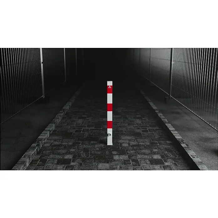 Schake Sperrpfosten - L x B x H: 70 x 70 x 1.300 mm, Stahl, Einbetonieren, Weiß/Rot, Öse - Warnbake mit rot-weißen Streifen in einer dunklen Gasse. Die Bake ist ein deutliches Warnzeichen in der tristen Umgebung.