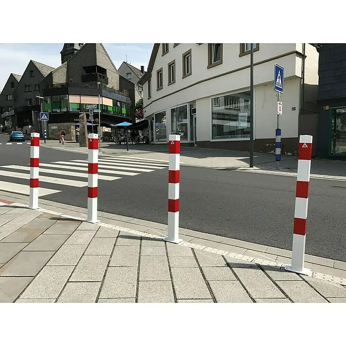 Schake Sperrpfosten - L x B x H: 70 x 70 x 1.300 mm, Stahl, Einbetonieren, Weiß/Rot, Öse - Nahaufnahme von rot-weiß gestreiften Absperrpfosten am Straßenrand, die Fußgänger schützen und die städtische Sicherheit erhöhen.