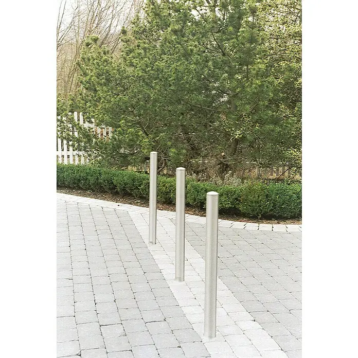 Schake Sperrpfosten - Ø x H: 76 x 900 mm, Edelstahl, Aufdübeln, Silber - Drei silberne Pfosten auf einem gepflasterten Weg dienen als stilvolle und funktionale Absperrung. Sie fügen sich nahtlos in die natürliche Umgebung ein.