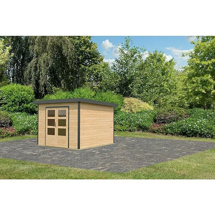 Karibu Gartenhaus Pluto 6 A - Außenmaß inkl. Dachüberstand (B x T): 309 x 292,4 cm, Holz, Naturbelassen/ Anthrazit - Ein modernes Holzgartenhaus mit Doppeltür und dunklem Rahmen, platziert auf einer gepflasterten Fläche, umgeben von üppigem Grün.
