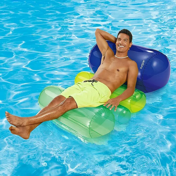 Funsicle Luftmatratze Schwimmlounge - Länge: 127 cm - Ein Mann entspannt auf einer grünen und gelben Luftmatratze im Pool, mit einer blauen Rolle als Kopfstütze, genießt die Sonne und das kühle Wasser.