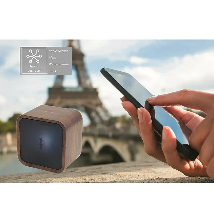 Intertechno Steuerzentrale Smart Home Selection-Zentrale - Braun, L x B x H: 80 x 80 x 61 mm - Elegantes Smart Home Gerät mit Holzgehäuse und Konnektivität zu Apple, Alexa und IFTTT vor dem Hintergrund des Eiffelturms.