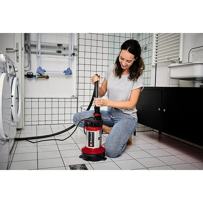 Einhell Schmutzwasserpumpe ECO GE-DP 7535 N LL - Max. Fördermenge: 18.500 l/h - Eine Frau kniet im Badezimmer und bedient eine Einhell Schmutzwasserpumpe, um den Raum von Wasser zu befreien.