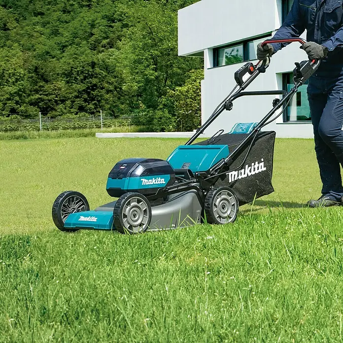 Makita XGT 40V max. Akku-Rasenmäher LM002GZ - 40 V, Ohne Akku, Schnittbreite: 53 cm - Ein Akku-Rasenmäher der Marke Makita wird auf einem grünen Rasen von einer Person bedient, um den Rasen zu mähen.