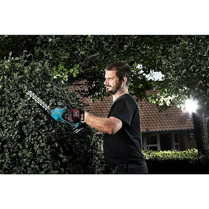 Makita LXT 18V Akku-Gras- & Strauchschere DUM604RFX1 - 18 V, Li-Ionen, 1 Akku - Ein Mann schneidet eine Hecke mit einer Makita Akku-Heckenschere im Garten, das Produkt ist perfekt für die Gartenarbeit.