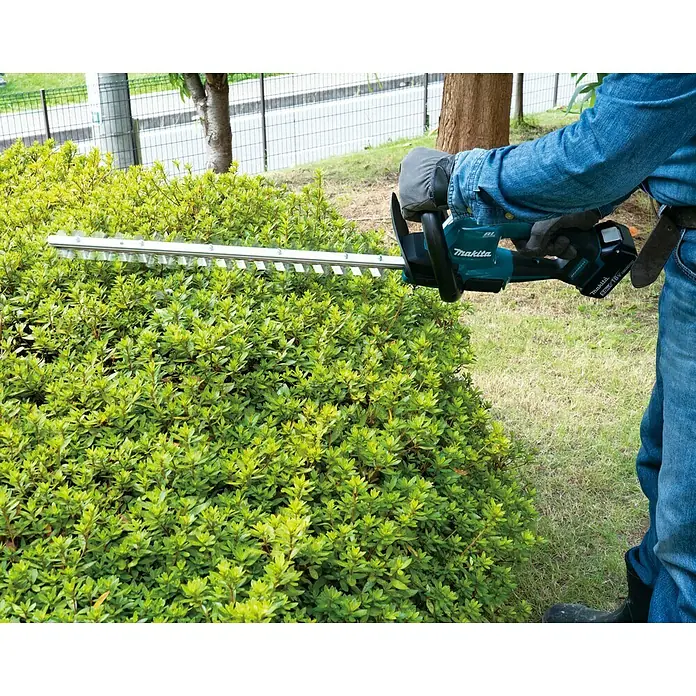 Makita LXT 18V Akku-Heckenschere DUH506Z - 18 V, Li-Ionen, Ohne Akku, Schnittlänge: 50 cm - Ein Mann benutzt eine Makita Akku-Heckenschere, um eine grüne Hecke zu schneiden, mit Fokus auf das Werkzeug und dessen Verwendung.
