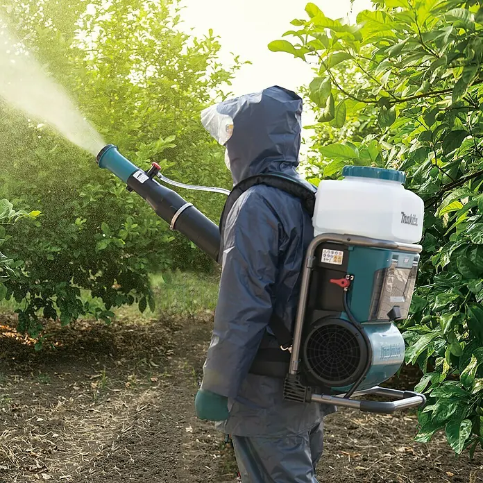 Makita XGT 40V max. Akku-Sprühgerät PM001GZ01 - 40 V, Ohne Akku, 15 l - Ein professioneller Gärtner sprüht mit einem Makita Akku-Rückensprüher eine grüne Pflanze, geschützt durch Schutzkleidung, im Freien.