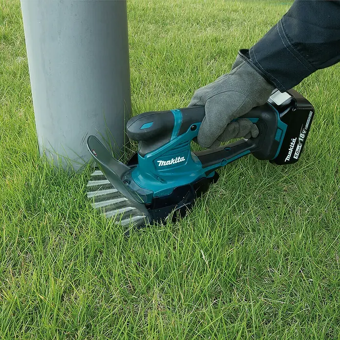 Makita LXT 18V Akku-Gras- & Strauchschere DUM604RFX1 - 18 V, Li-Ionen, 1 Akku - Detailaufnahme einer Makita Akku-Grasschere im Einsatz, die präzise Rasenkanten schneidet. Ideal für Gartenpflegearbeiten.