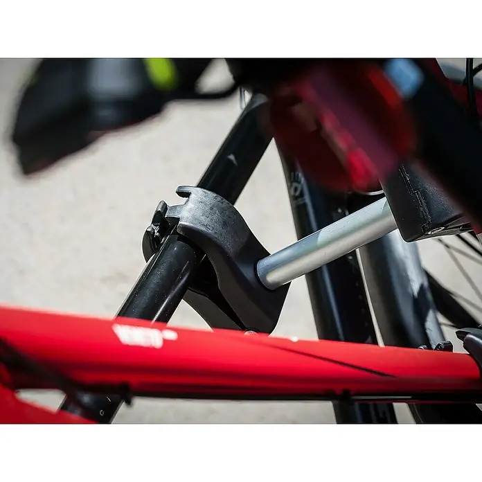 Eufab Rahmenhalter - Kurz, Durchmesser: 3 cm - 6 cm, Länge: 12 cm - Nahaufnahme eines Fahrradanhängers, der an einem Fahrrad befestigt ist, mit Fokus auf die Kupplung. Die Konstruktion wirkt robust und zuverlässig.