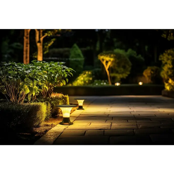 Garza Goliat Sobremuro solar LED con sensor - 3.000 K - 4.000 K, 2.200 lm, IP65 - Paisaje de jardín iluminado que muestra luces de jardín modernas que proyectan un brillo cálido en el camino pavimentado.