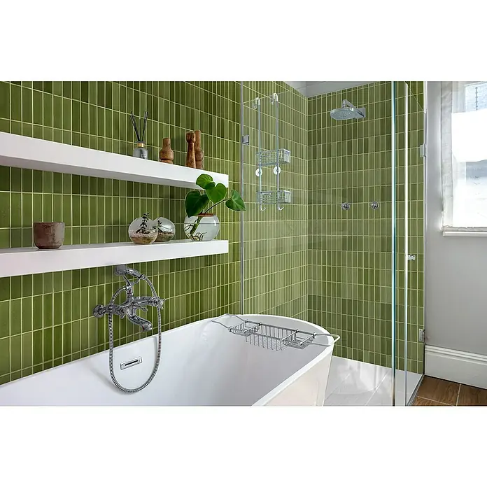 Bariperfil Revestimiento de pared de PVC Olive Tile - 260 x 33,3 cm, Olive - Elegante baño con azulejos verdes, estantes blancos y bañera exenta. Un panel de vidrio separa la zona de ducha.