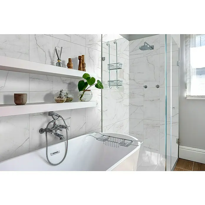 Bariperfil Revestimiento de pared de PVC White Storm - 260 x 33,3 cm, Blanco - Baño con bañera y ducha de lluvia. Los azulejos de mármol blanco crean un ambiente sereno con estantes flotantes para detalles decorativos.