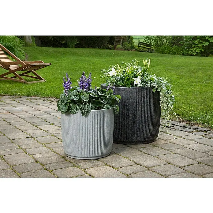 Scheurich Pflanzkübel rund Linetto - Außenmaß (Ø x H): 38,6 x 35,2 cm, Kunststoff, Stony Grey - Zwei gerillte Pflanzgefäße in Grau und Anthrazit mit üppigen Pflanzen auf einer gepflasterten Terrasse, ein stilvolles Highlight für jeden Garten.