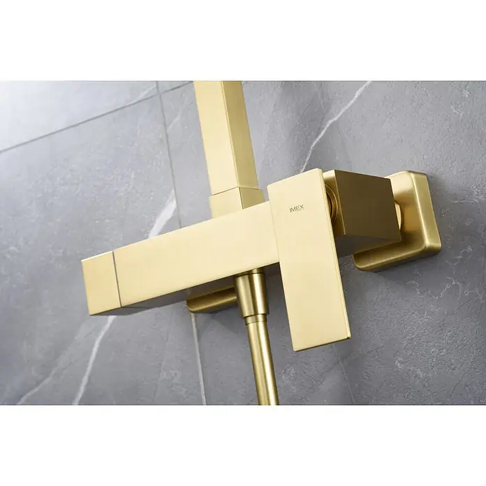 Imex Pisa Sistema de ducha - Grifo monomando, Oro - Primer plano de un elegante grifo de ducha IMEX dorado montado en una pared de mármol gris, mostrando un diseño moderno y artesanía de calidad.
