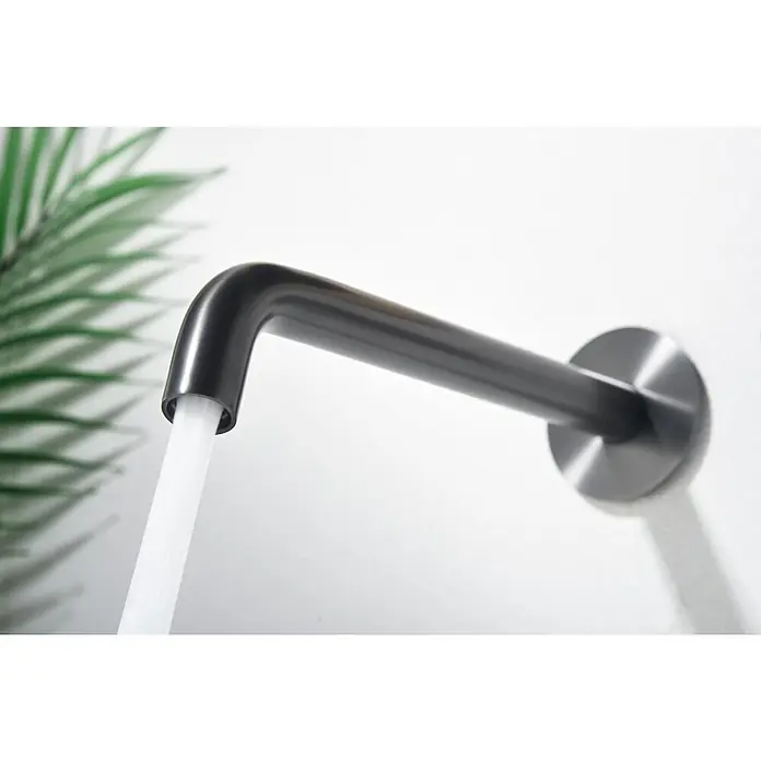 Imex Génova Grifo de lavabo - Black gun metal - Primer plano de un moderno grifo negro mate con agua corriente sobre un fondo blanco y hojas verdes.
